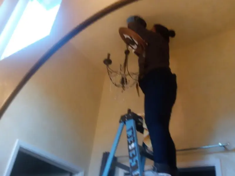 Electrician installing a chandelier in a Lacy-Lakeview residence